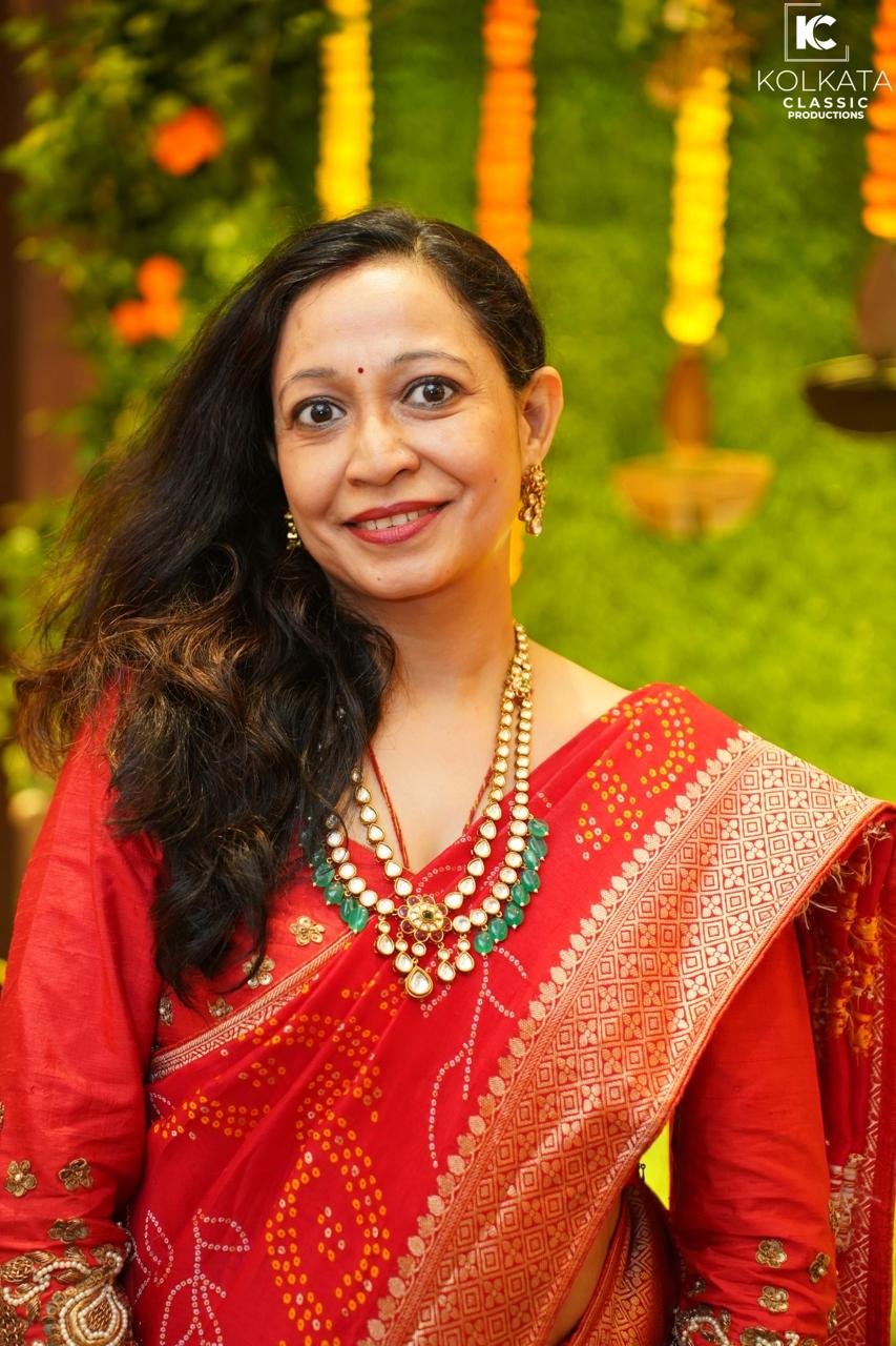 Smita Modi in a red bandhani saree wearing a Kundan Jadau necklace with emerald drops